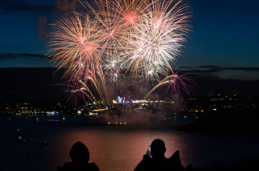 silhouette of two person taking photo of fireworks