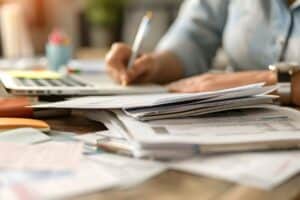 Schreibtisch mit Belegen, Taschenrechner und Laptop bei der Büroarbeit